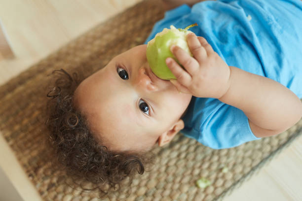 istock Cute Baby Boy Eating Apple 1209907493
