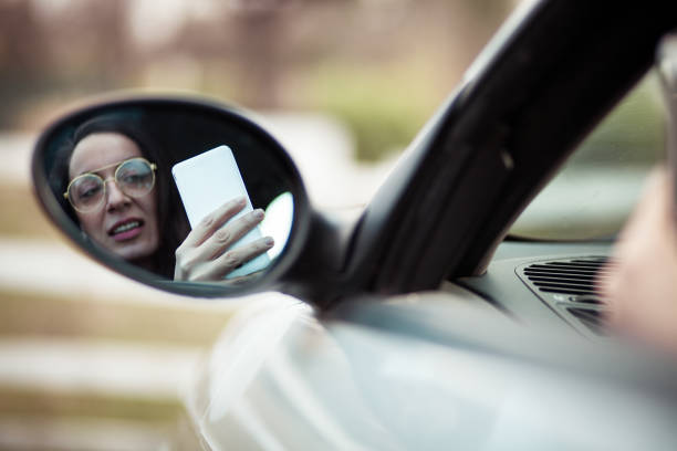 giovane donna guida auto e usa telefono - car phone foto e immagini stock