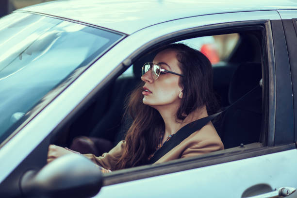 istock Young woman driving car 1209908120