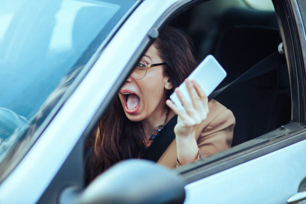 giovane donna guida auto e usa telefono - car phone foto e immagini stock