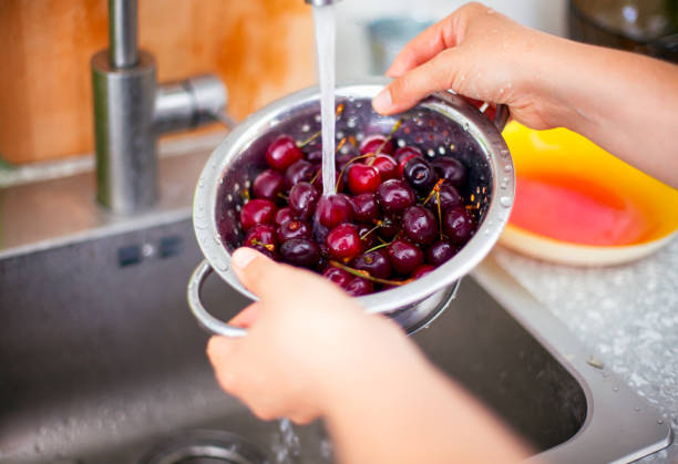 istock Woman hands washing cherries in colander in kitchen sink. 1209909523