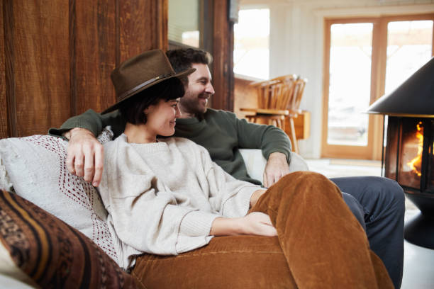 istock Smiling young couple warming up by a fireplace in their cabin 1209909962