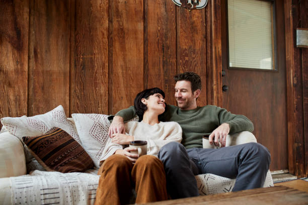 istock Smiling couple drinking coffee and talking together on their sofa 1209910246