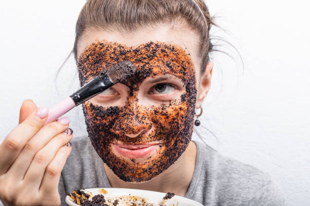 istock Satisfied young attractive woman apply face scrub - coffee cleansing scrub 1209911160
