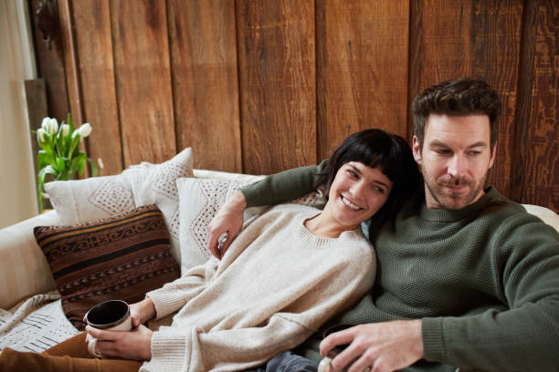 istock Young couple relaxing together on a sofa and smiling 1209911505