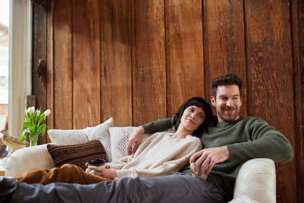 istock Smiling young couple relaxing together on a sofa 1209911595