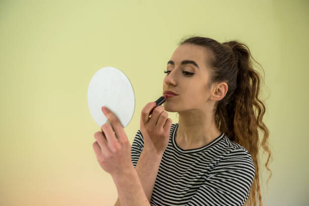 istock beautiful brunette girl using pink lipstick doing makeup morning before work isolated on green 1209912921