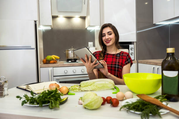 istock Young woman using a tablet computer to cook different vegetables in her kitchen for everything about healthy nutrition. 1209913025