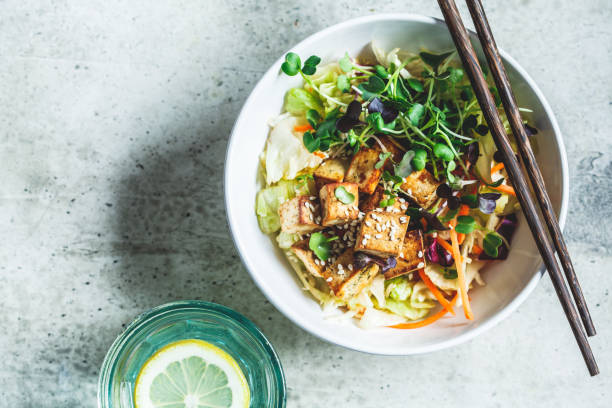 Fried tofu salad with sprouts and sesame seeds in white bowl, top view. Vegan food, asian food concept. Fried tofu salad with sprouts and sesame seeds in a white bowl. Vegan food, asian food concept. tofu photos stock pictures, royalty-free photos & images