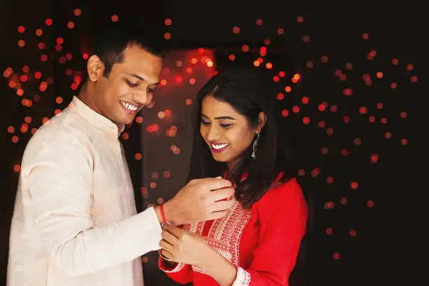 Indian woman tying rakhi on her brother's hand to celebrate Raksha Bandhan (Rakshabandhan) / Bhai dooj