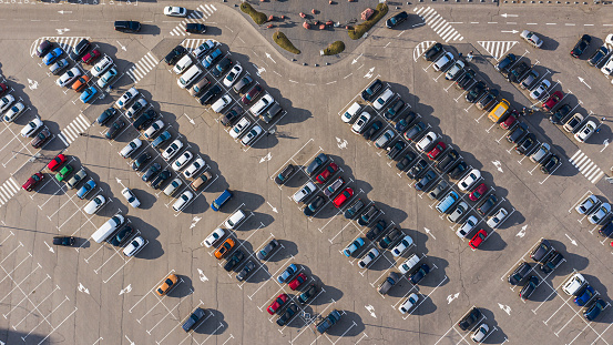Crowded car parking with colorful cars on parking spaces. A shot from the drone top view from a height of 100 meters.