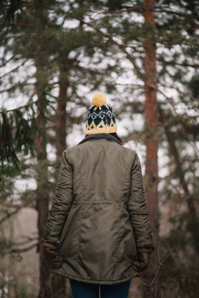 istock Backside of a girl standing in the forest 1209917074
