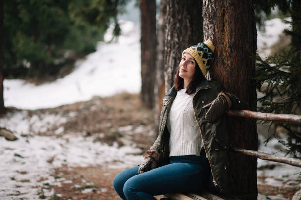 istock Brunette woman sitting on a bench in woods 1209918091