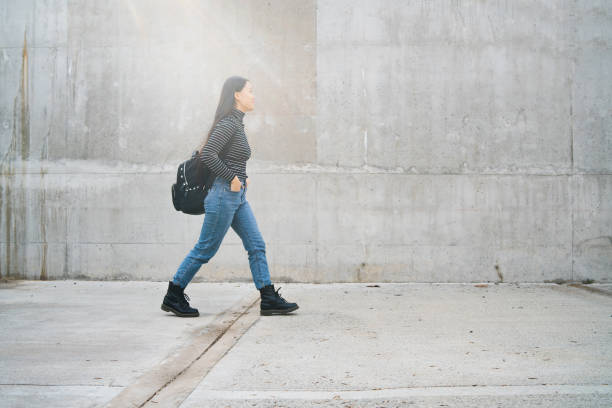 istock Asian woman walking against grey wall. 1209921952