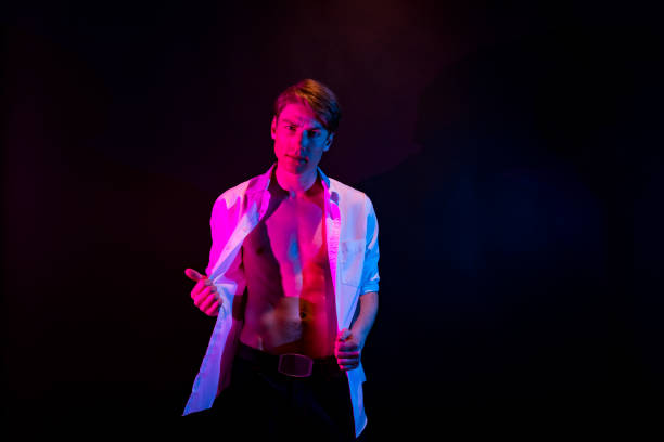 istock Caucasian young male stripper in front of colored background wearing button down shirt 1209922433