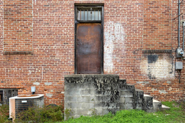 A white brick wall, door, sidewalk and utility pole.