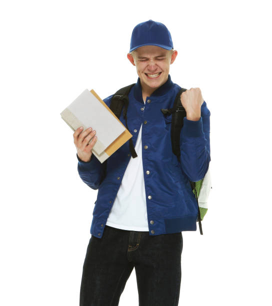 joven estudiante universitario caucásico en frente de fondo blanco usando mochila y libro de sujeción - attractive male men baseball cap male fotografías e imágenes de stock