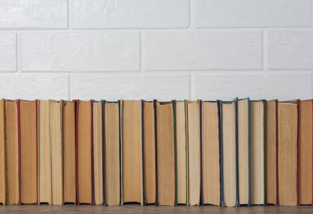 istock A stack of old books. Bookstore, library, bookshelf. Vintage, retro, antique. Study, education, school, University. Literature, history, science. Books against a white brick wall. 1209925812