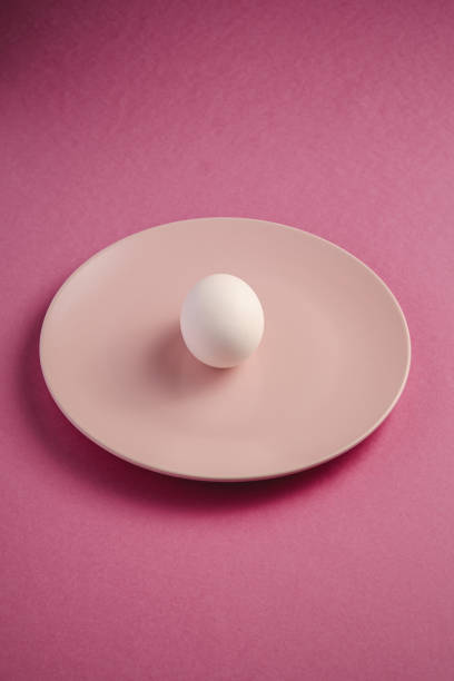 istock White egg in pink plate on purple plain minimal background, angle view, happy Easter day 1209926283