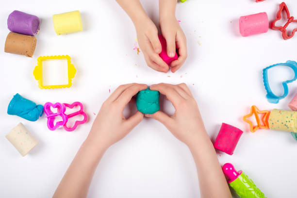 istock Children hands playing with colorful modeling clay on white background. 1209926382