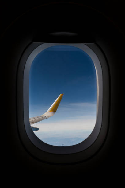 view of the sky and the wing of an airplane from the inside airplane window overlooking one of the wings, in full flight. You see a blue sky with clouds. Airplane travel. view from the inside gliding stock pictures, royalty-free photos & images