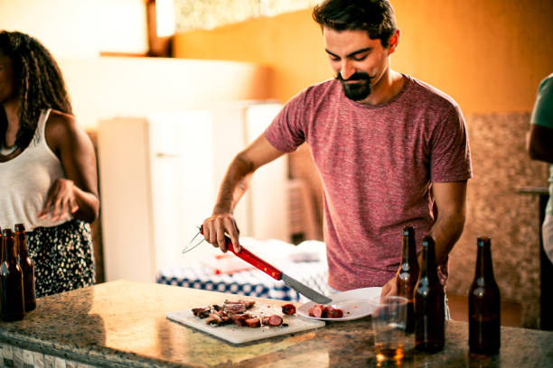 Handsome hipster guy serving barbecue sausages in a barbecue party Handsome hipster guy serving barbecue sausages in a barbecue party. Canon gear. brazilian bbq stock pictures, royalty-free photos & images