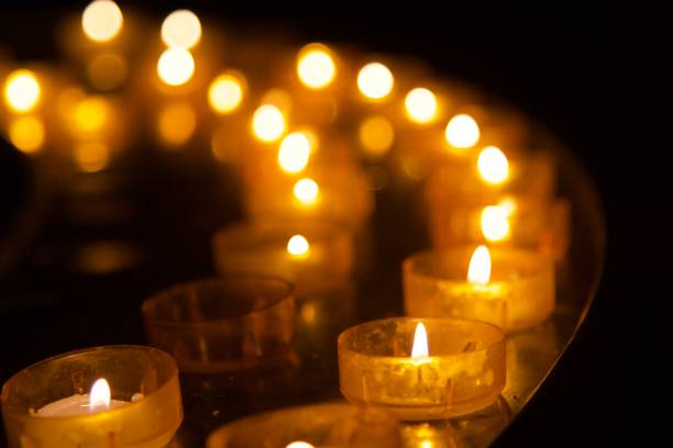 bougies votives de lumière de thé allumées dans une rangée - candle memorial vigil praying candlelight photos et images de collection