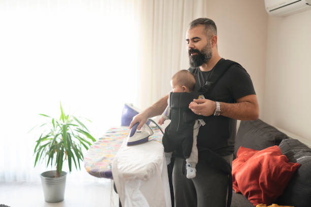 istock Young father ironing clothes and carrying his little daughter 1209934487