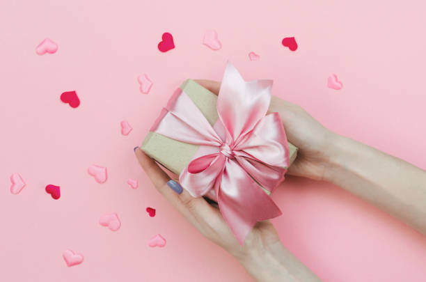 istock Hands Holding a Valentine's Day Present on Pink Background. 1209940174