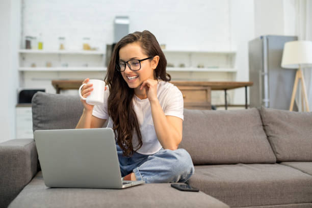 istock Happy young lady using laptop in living room 1209940193