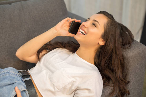 istock Smiling cute lady using mobile phone at home 1209940297