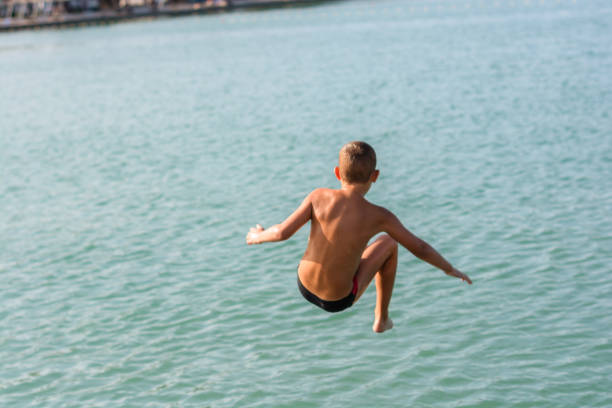 istock Child boy jumping into the sea 1209941466