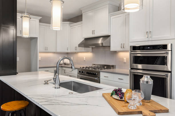 beautiful kitchen in new luxury home with island, pendant lights, and hardwood floors. kitchen in newly constructed luxury home quartz stock pictures, royalty-free photos & images