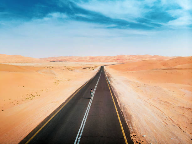 woman scenic desert road in liwa uae aerial - liwa desert stock-fotos und bilder