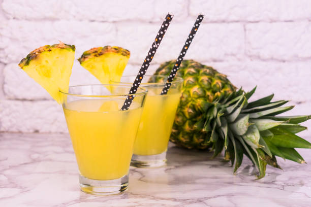 istock glasses of fresh pineapple juice and pineapple on a table on a white background. 1209944740