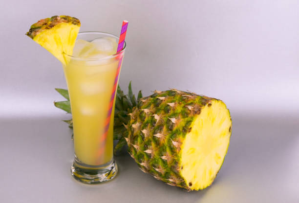 istock Pineapple juice in a tall glass and pineapple on a gray background. 1209944896