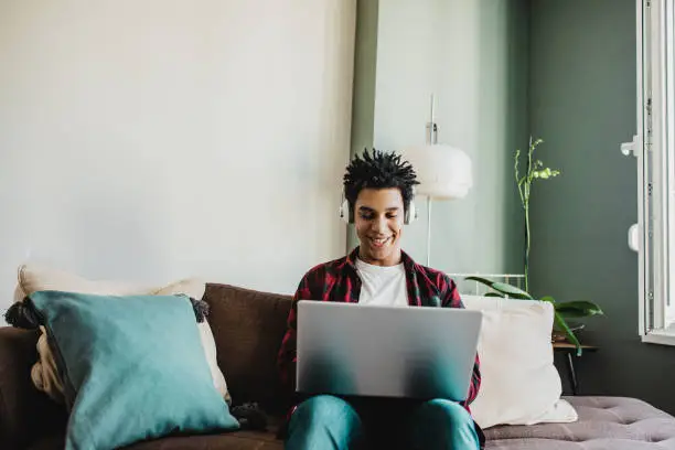 Young african-american man is using laptop at home
