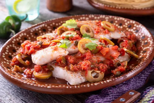 A plate of delicious fish veracruz with olives, tomato, onion, capers and serrano pepper.
