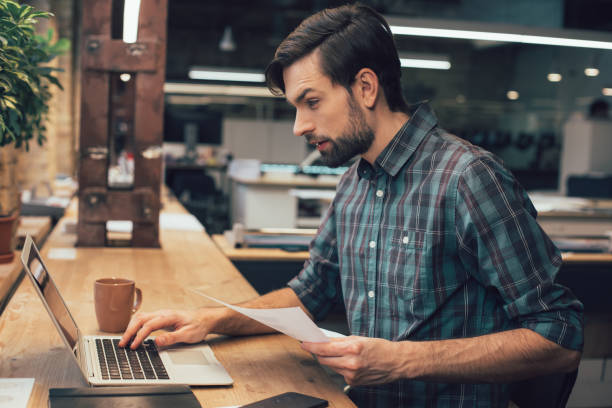 istock Attentive man working with gadget and documents stock photo 1209951029