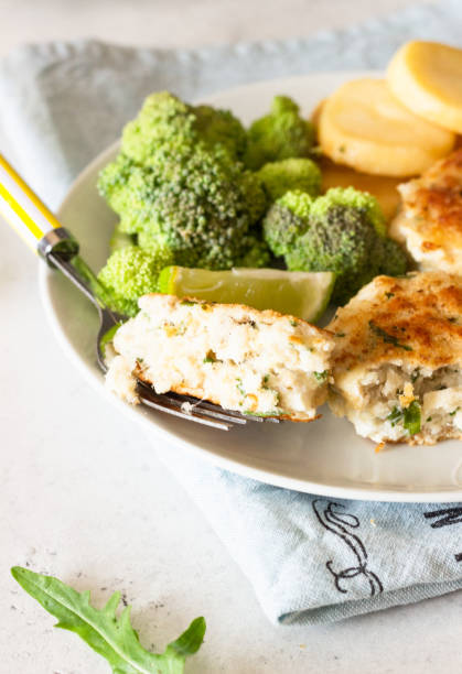 istock Delicious cutlets (fish or meat) with broccoli, potatoes and sauce on a plate. Light grey stone background. 1209953345