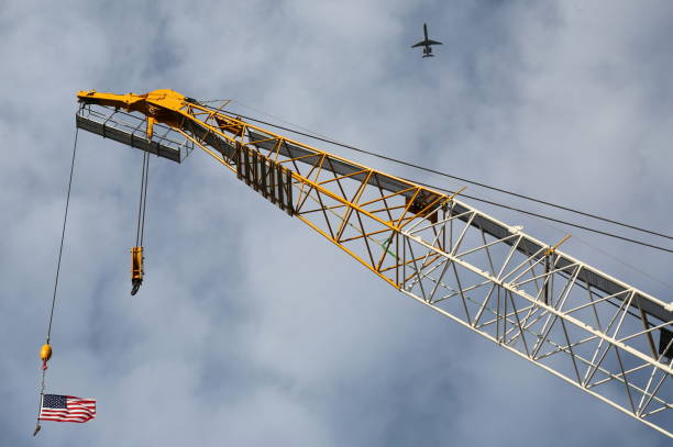 United States flag on a construction crane in a sunny morning in New York city with a plane departing La Guardia airport
