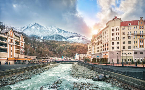 Mzymta River and the snowy peaks of the mountains View of the houses, hotels, shops, the Mzymta River and the snowy peaks of the mountains on Rosa Khutor in Sochi on a sunny day. sochi stock pictures, royalty-free photos & images