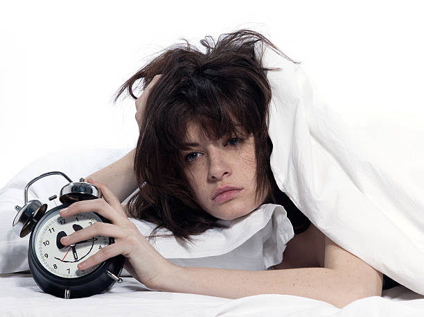 mujer en la cama sosteniendo el reloj despertador despertar cansado - sleeping insomnia alarm clock clock fotografías e imágenes de stock