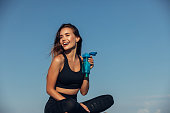 Fitness woman drinks water in front of sea background