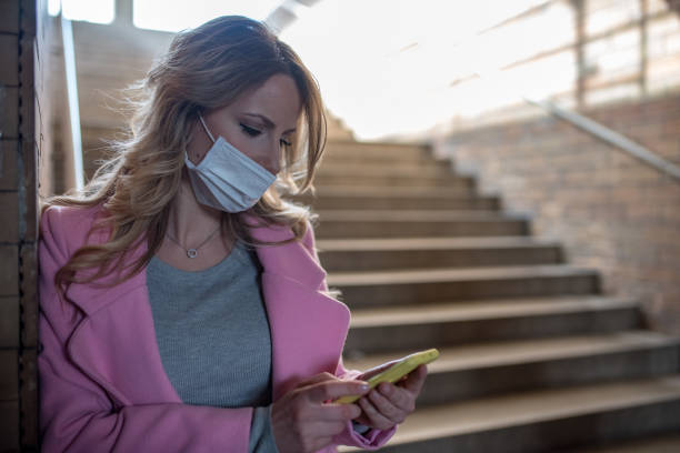 istock Young woman with protective mask is using phone. 1209958218