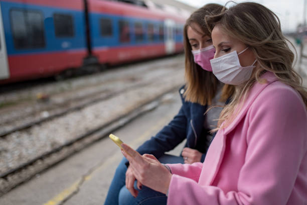 istock Two girls with protective masks waiting for train 1209958574