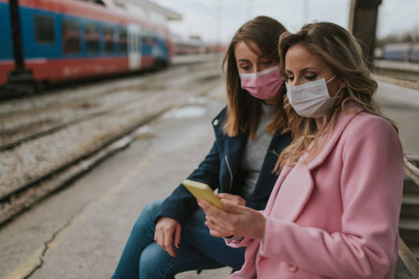 istock Two girls with protective masks waiting for train 1209958583