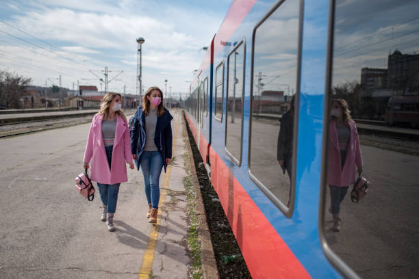istock Two women with protective masks passing by the train 1209958674