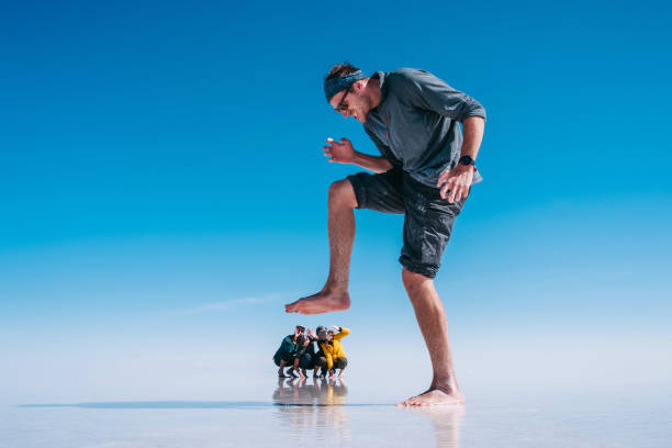 touristes à uyuni salt flats aka salar de uyuni en bolivie, amérique du sud, perspective forcée - diminishing perspective photos photos et images de collection