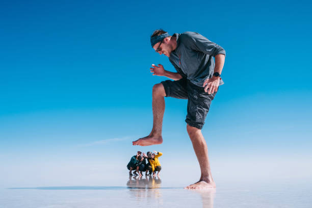 Tourists at Uyuni Salt Flats aka Salar de Uyuni in Bolivia, South America, Forced Perspective Fun forced perspective shot of young tourists at Uyuni Salt Flats (Spanish: Salar de Uyuni ) in Bolivia, South America. giant fictional character stock pictures, royalty-free photos & images
